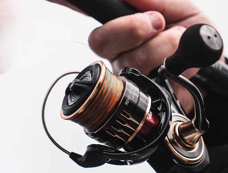 Revelry HD MQ spinning reel in black, gold and red, held on a rod